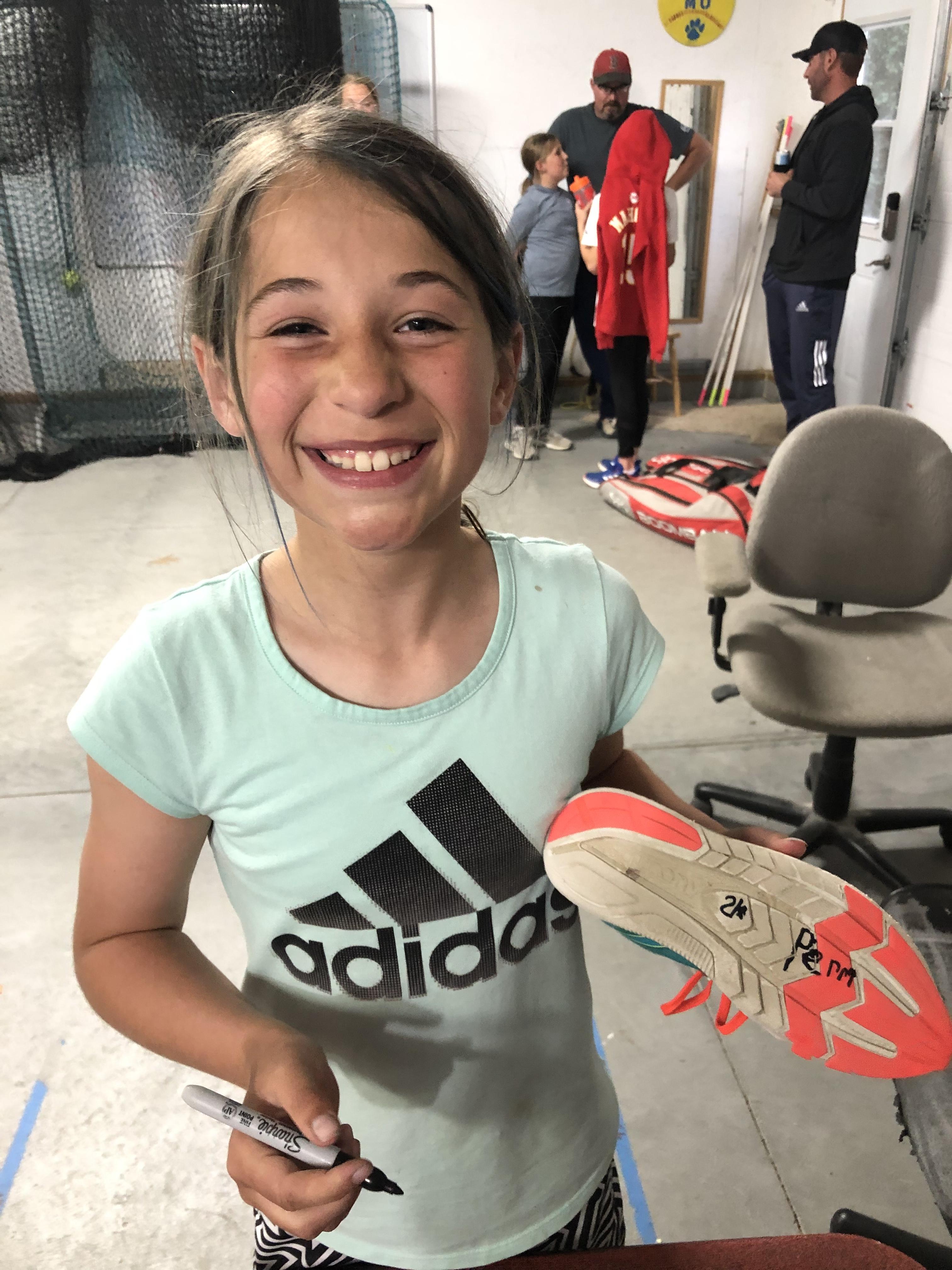 Player smiling while signing an autograph on a cleat