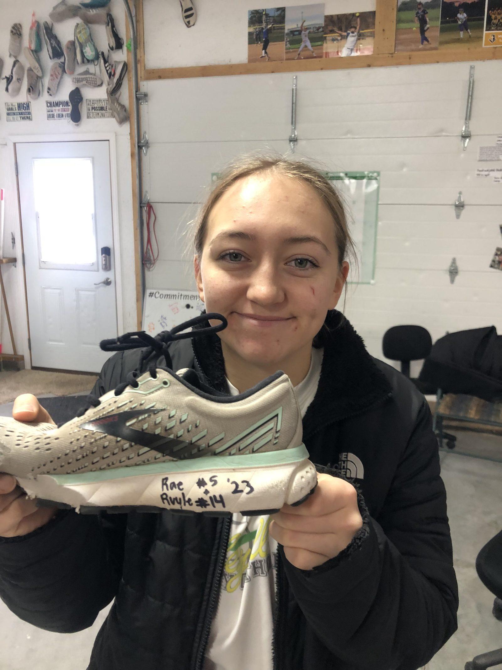 Player smiling while holding a shoe signed by teammates