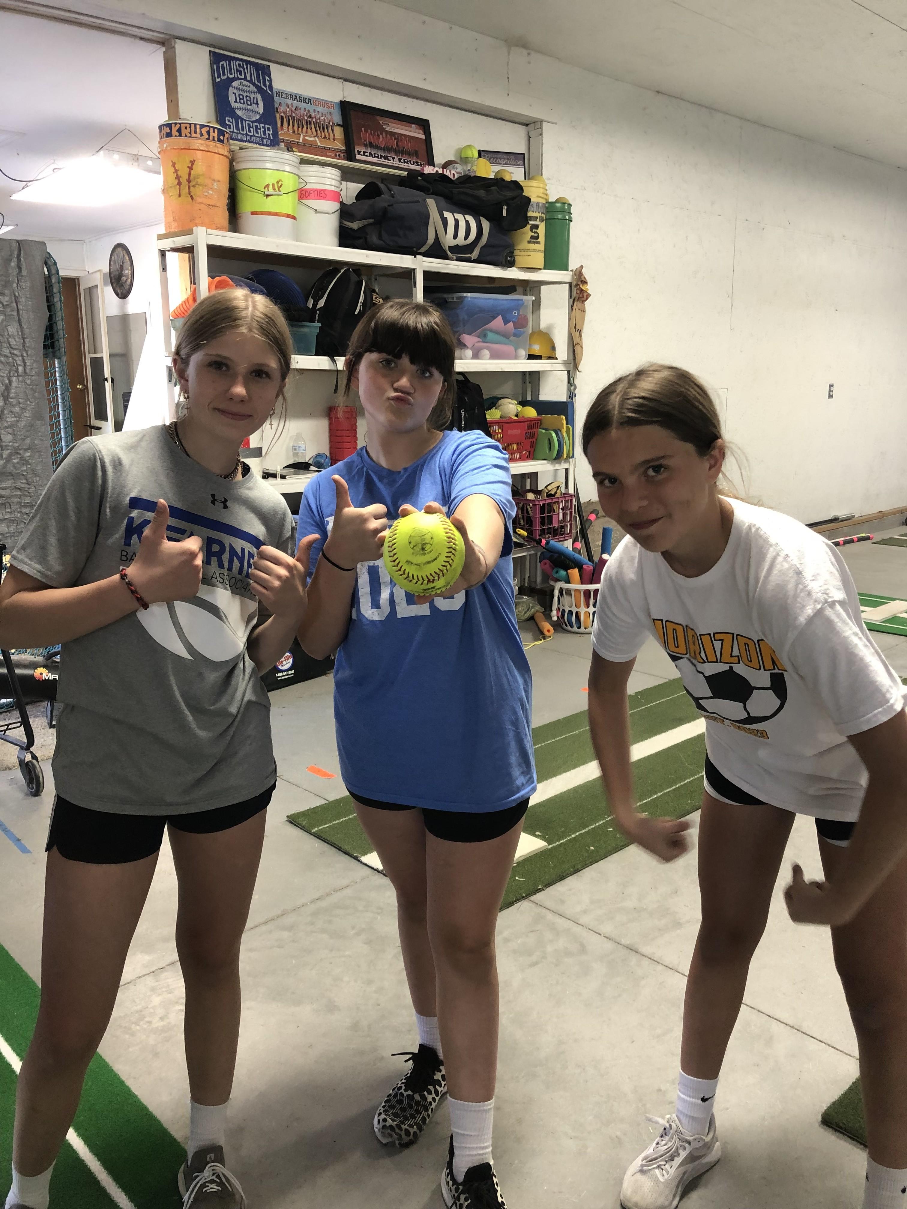 Teammates posing together holding a softball