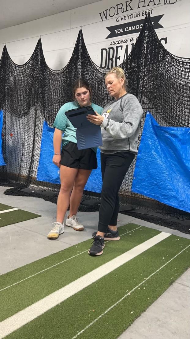 Coach reviewing pitching data on a tablet with an athlete