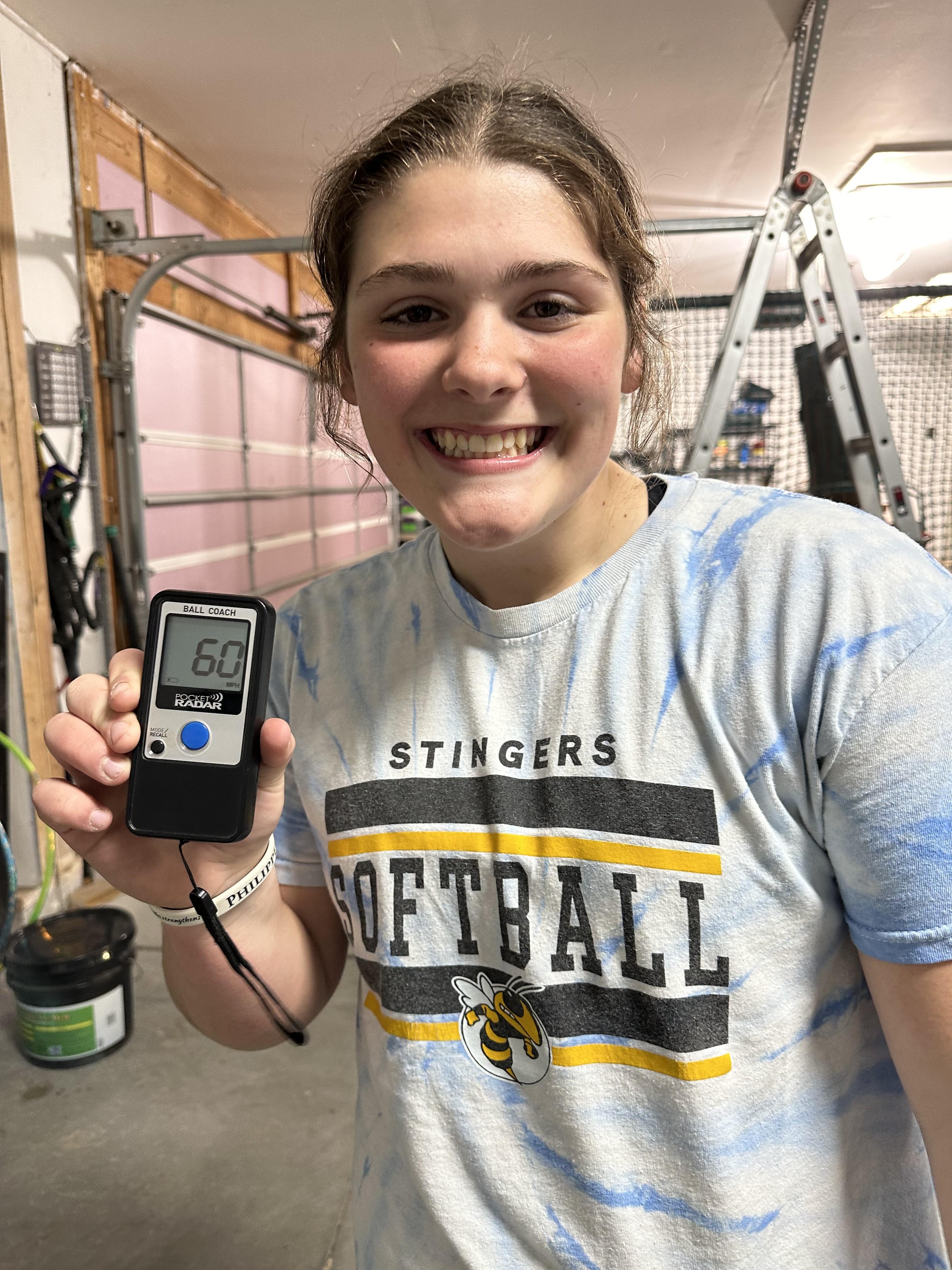 Stingers Softball player holding a radar gun reading 60 mph