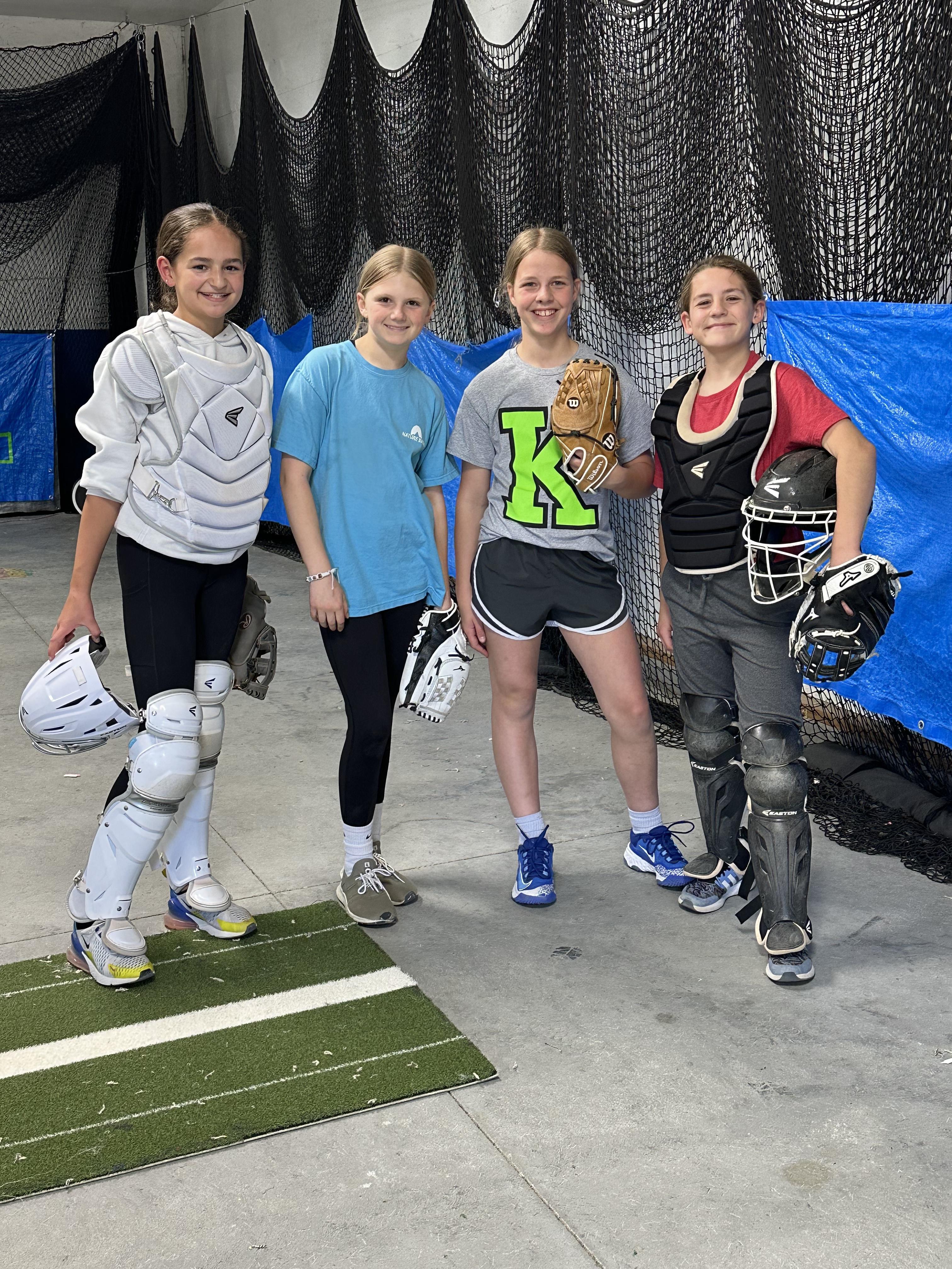 Four catchers and players in gear posing together at the training facility