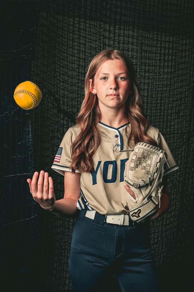 York softball player tossing a ball with glove ready