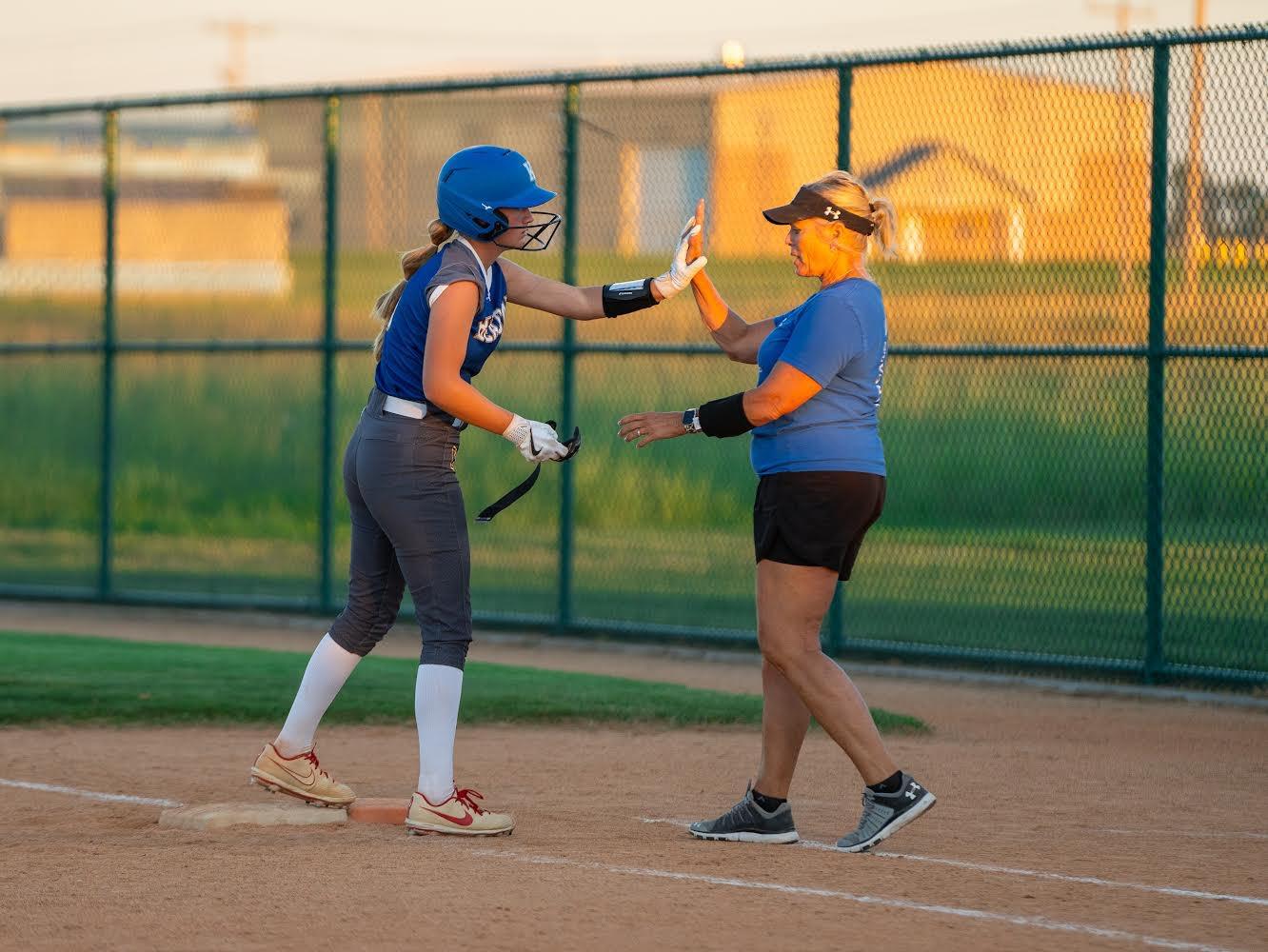 Player receiving a high five from coach at base